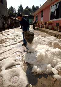 Un menor recoge el granizo en el patio de su casa, luego de la fuerte lluvia en la noche del miércoles, que afectó a más de 200 personas del poniente de la ciudad