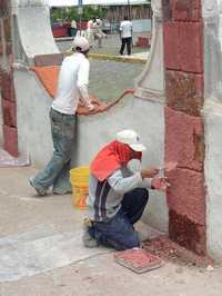 Albañiles aplanan con cal y arena un muro del atrio del templo de San Pedro Apóstol, acabado que contrasta con el estilo arquiitectónico del resto del inmueble histórico