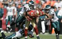 Arnaz Battle, de San Francisco, es tacleado por Quintin Mikell (arriba), Brian Dawkins y Lito Sheppard, de Filadelfia, en el partido que Águilas ganó 40-26